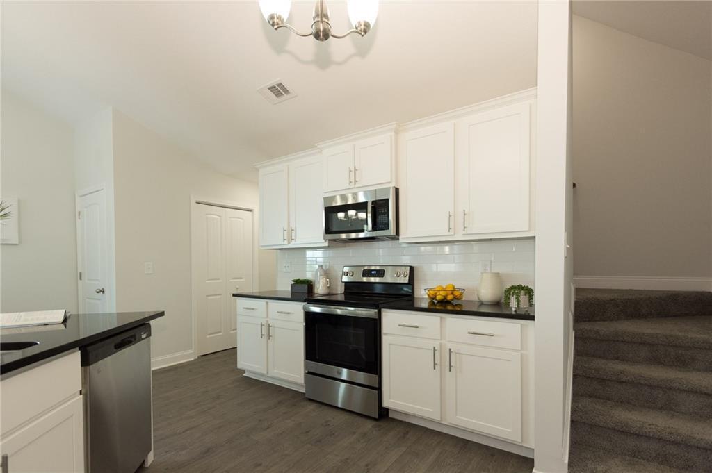 Kitchen with Painted White Cabinets and  Granite Counter Tops.  Stainless Steel Appliances.  Pantry.  Stairs to Bonus Room.  LVP Floors.  Vaulted Textured California Ceilings.  
