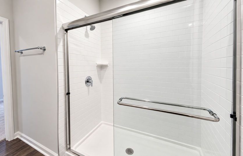 Walk-in shower with sleek glass doors and classic tile surround.