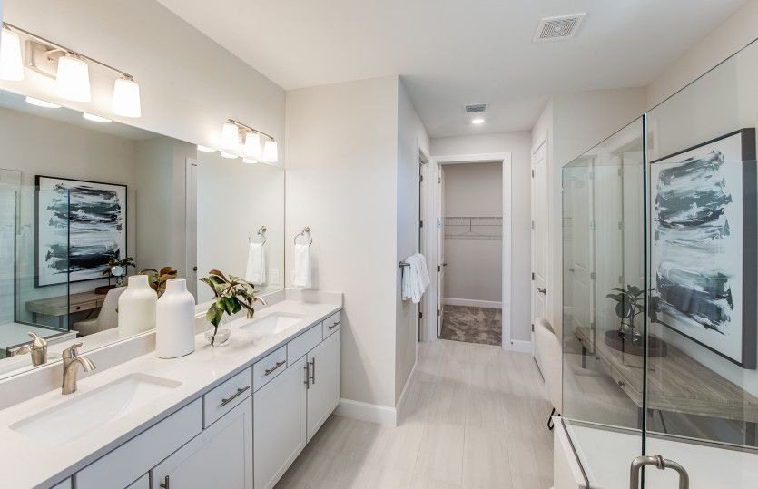Owner's bathroom with dual vanities and access to WIC