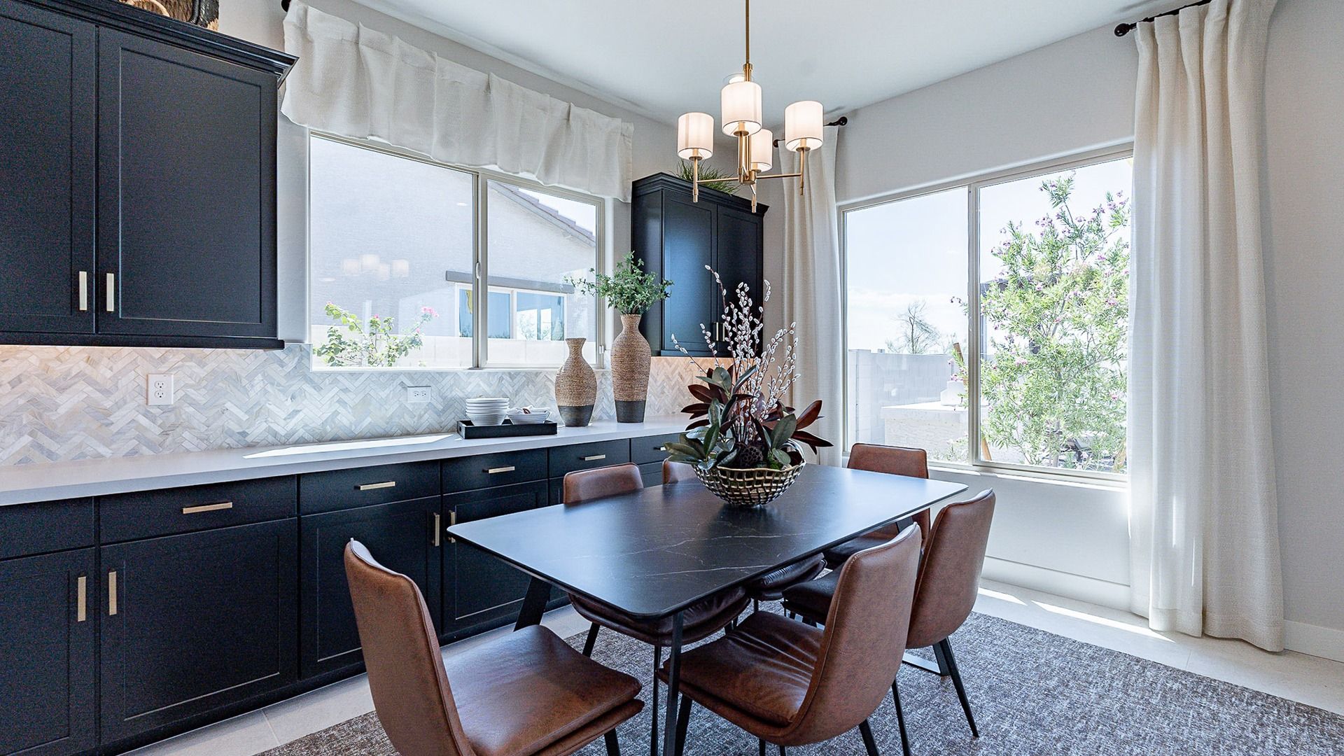 Luxurious dining space features sleek black cabinetry, chic herringbone tile, and expansive windows in Windrose.