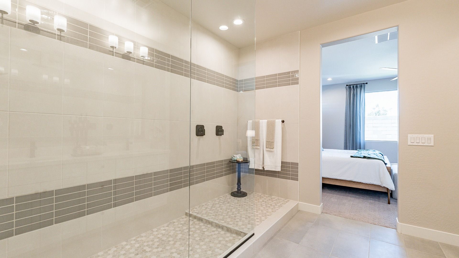 Elegant shower with designer tiles and seamless glass door in Sienna Park. Exquisite craftsmanship.
