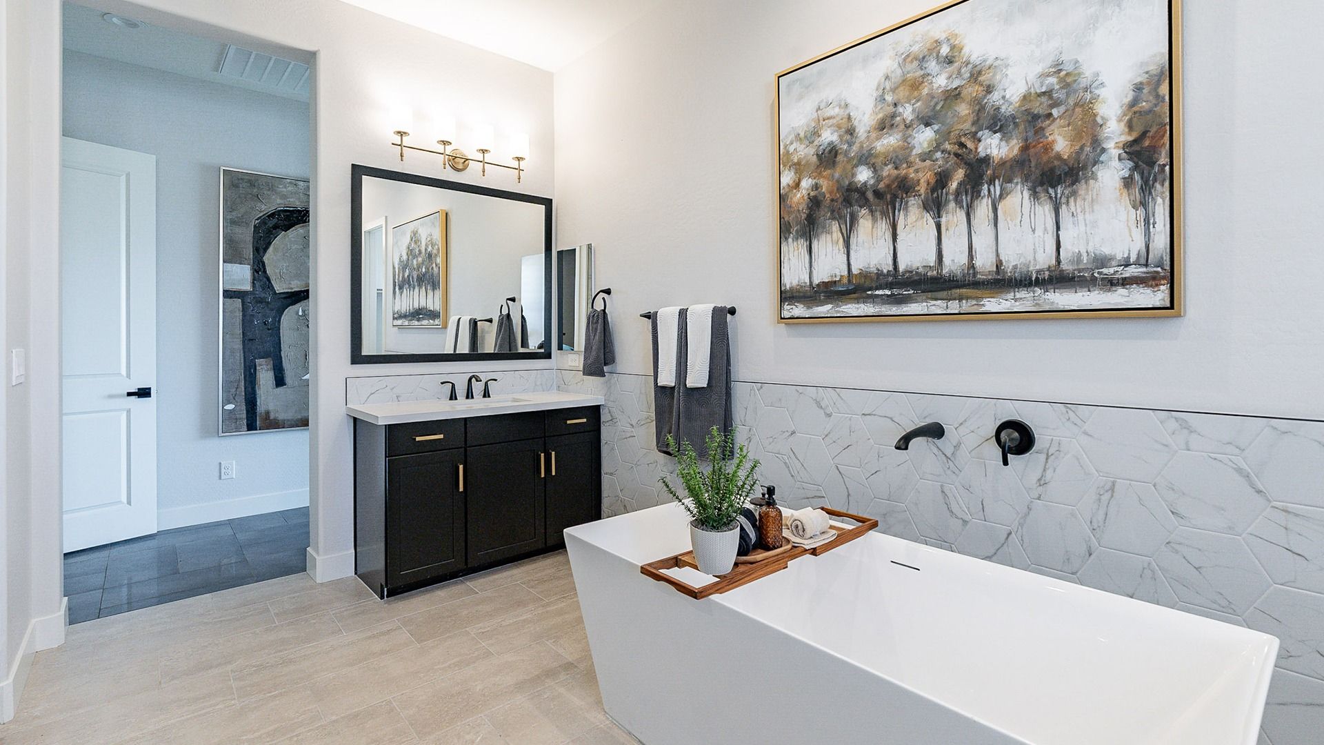 Exquisite freestanding tub with hexagonal tile accent in Windrose. Elegant black and white vanity.
