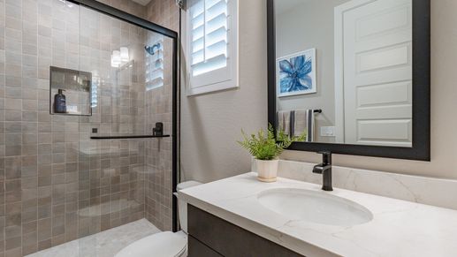 Sophisticated glass shower, sleek marble countertop, and elegant black fixtures at The Villas at Mystic.