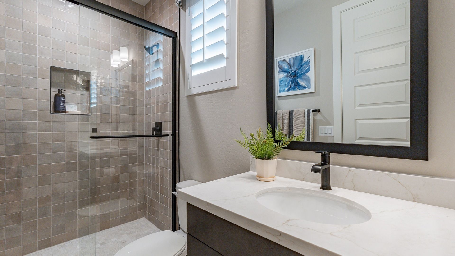Sophisticated glass shower, sleek marble countertop, and elegant black fixtures at The Villas at Mystic.