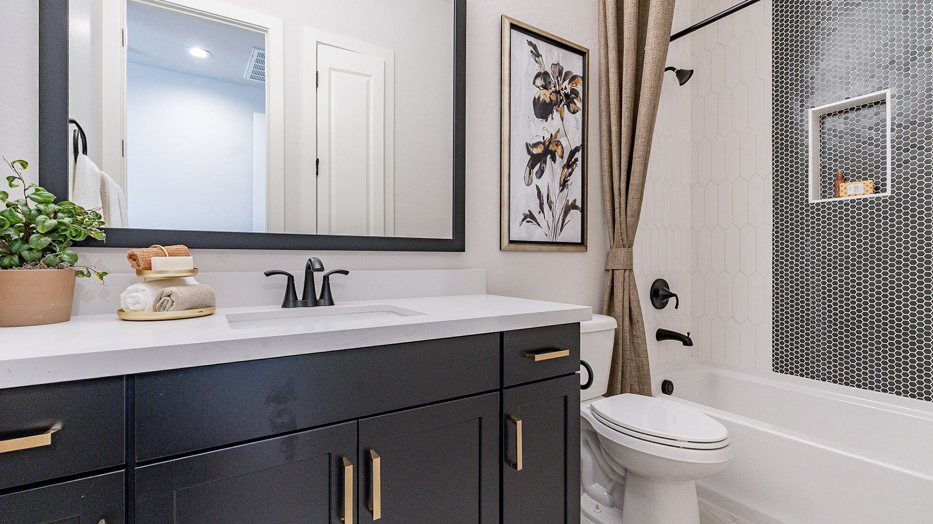 Sophisticated black vanity and hexagon wall tiles elevate this Windrose bathroom's elegance.