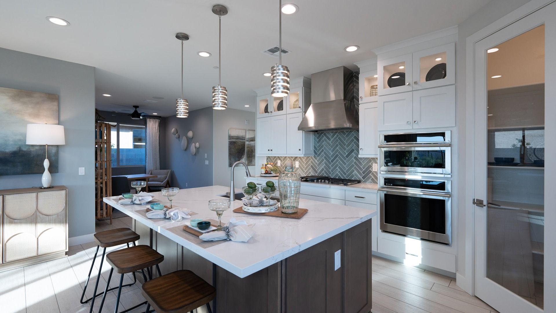Luxurious kitchen features marble countertops, herringbone backsplash, premium appliances in Mystic community.