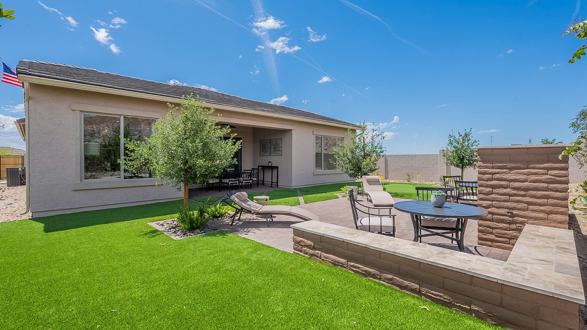 Pristine patio with elegant seating, manicured lawn, and expansive windows in Hacienda at Estrella.