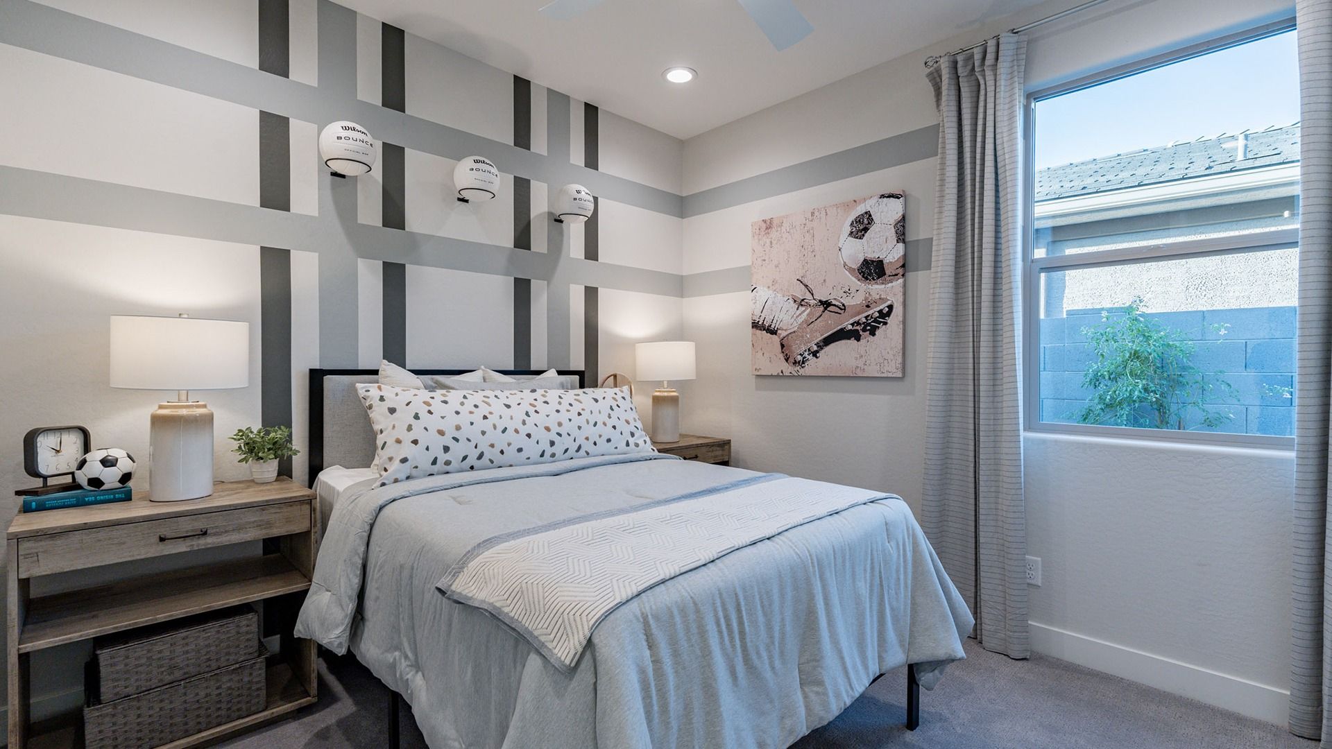 Sleek striped walls and plush bedding create a modern oasis in The Villas at Mystic community.