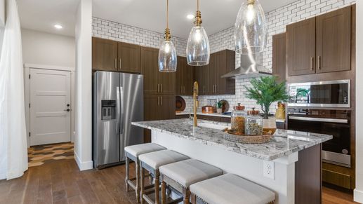 Exquisite granite countertops and pendant lighting elevate this Dillon Pointe kitchen's sleek, modern appeal.