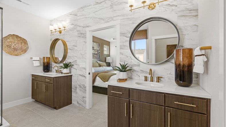 Dillon Pointe offers a refined bathroom featuring marble walls, dual vanities, and gold accents for a sophisticated look