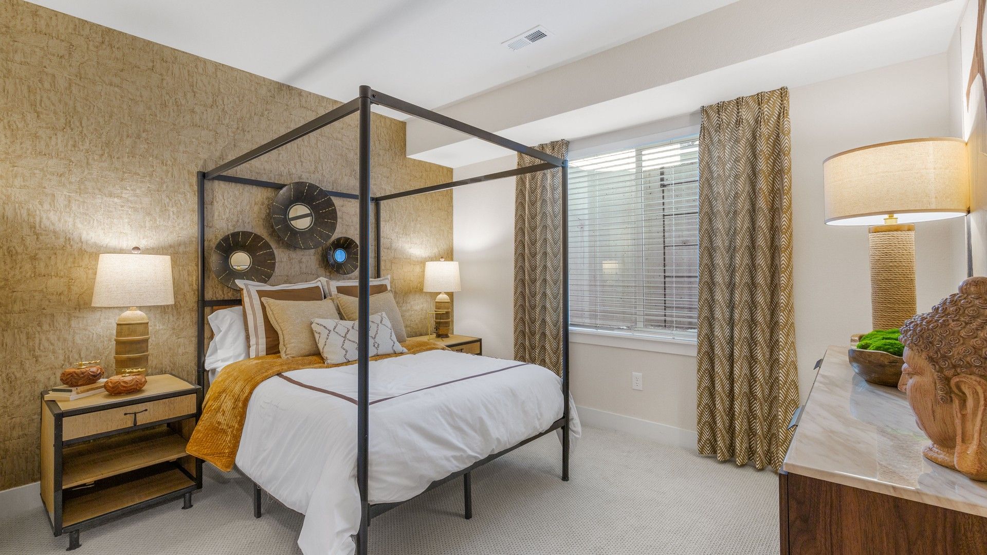 Opulent Dillon Pointe bedroom features a striking canopy bed and textured gold accent wall.