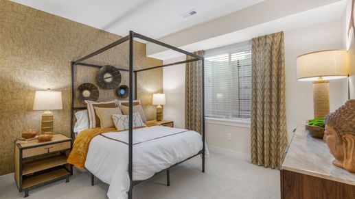 Opulent Dillon Pointe bedroom features a striking canopy bed and textured gold accent wall.