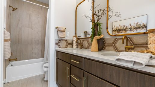 Elegant dual vanity with hexagonal tile backsplash and gold fixtures enhances Dillon Pointe's luxurious charm.