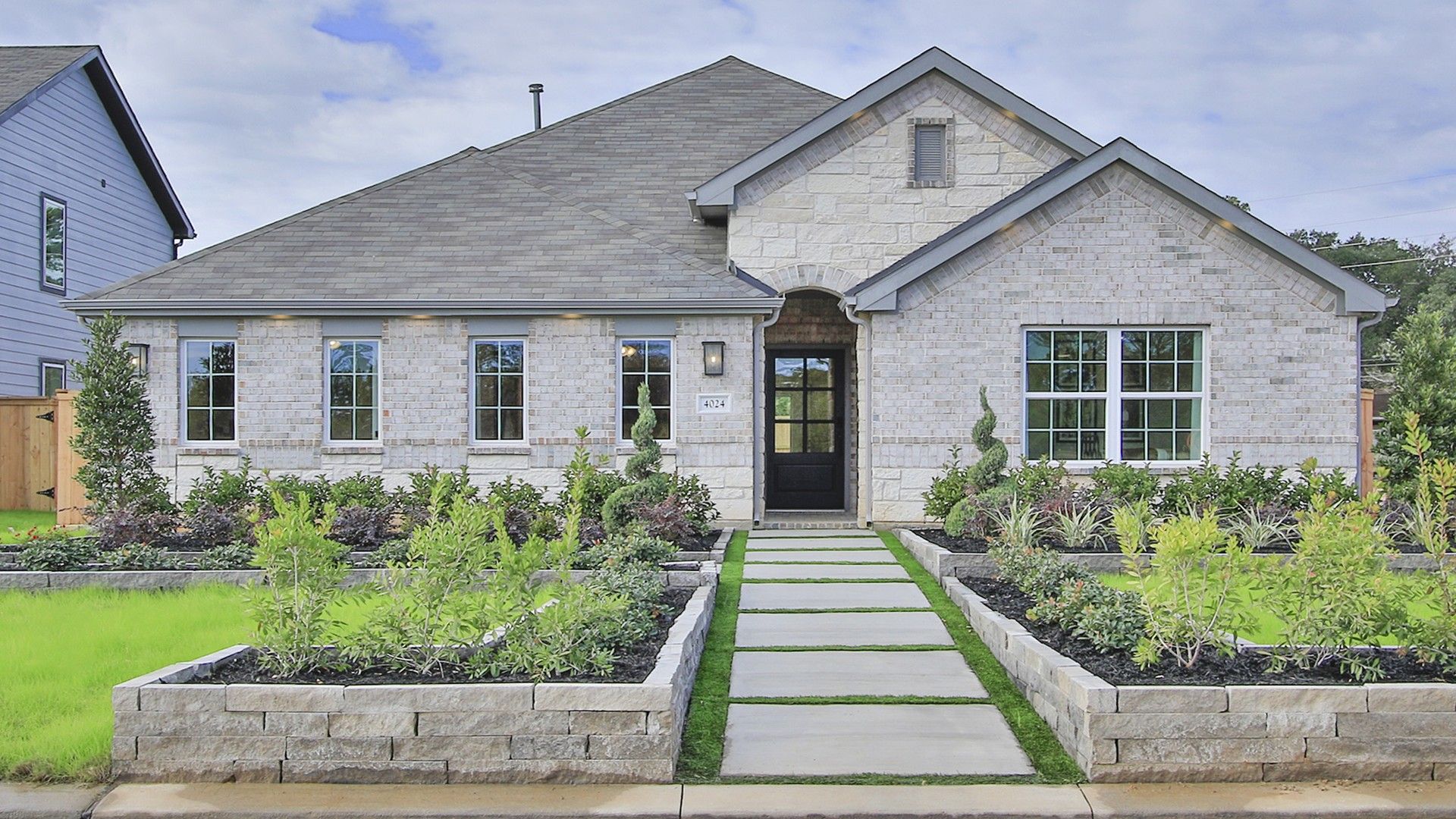 Luxurious stone facade with pristine landscaping in Colony at Pinehurst, Texas.