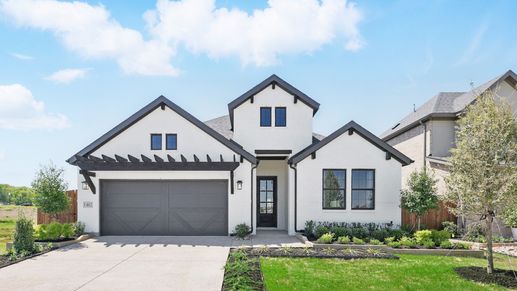 Sophisticated brick facade and gable roof elevate this Aldeana residence. Manicured landscaping adds elegance.