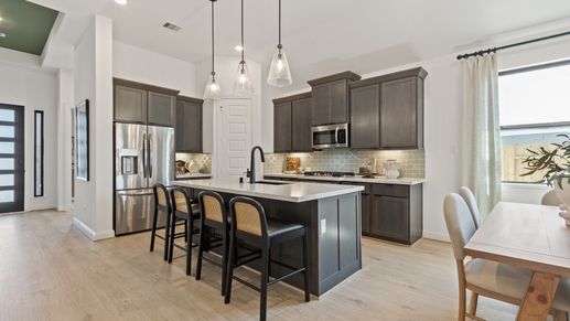 Experience elegance with high-end cabinetry, chic lighting, and a spacious island in Texas's Oakwood Estates.