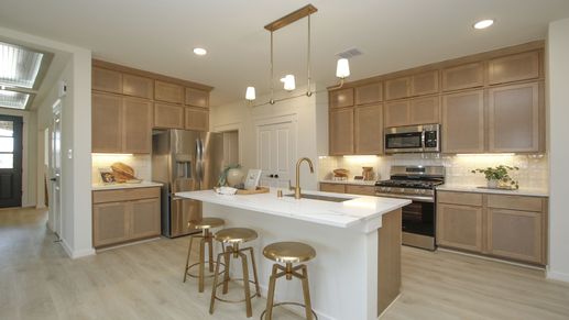 Elegantly designed kitchen featuring light wood cabinetry, sleek gold fixtures, and premium appliances in Cielo.