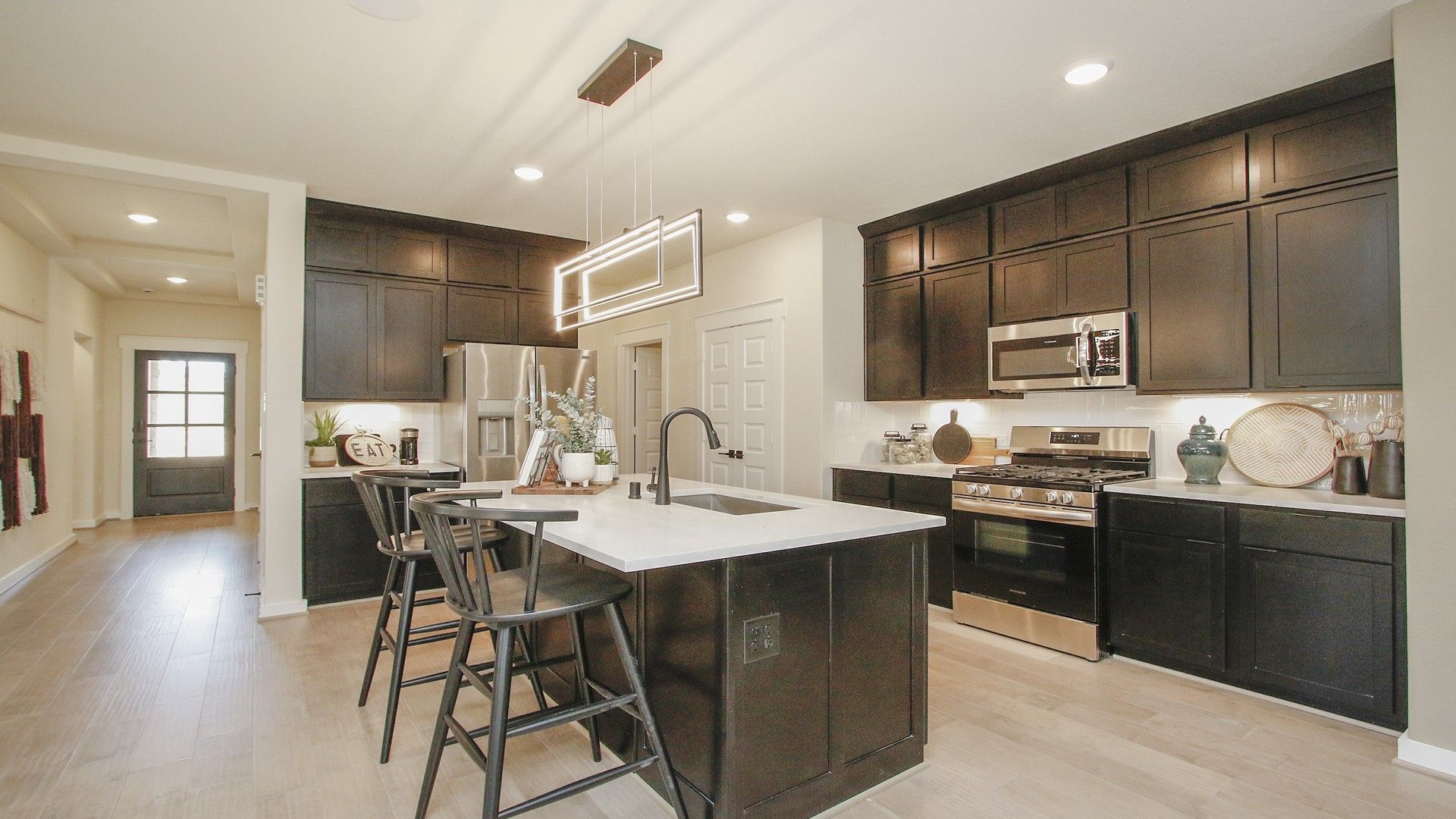 Elegant dark cabinetry and sleek pendant lighting enhance the sophisticated kitchen in Colony at Pinehurst.