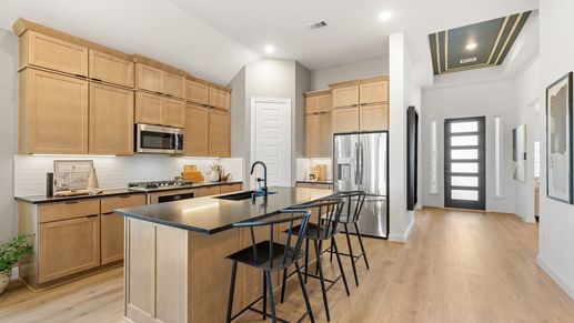 Premium light wood cabinetry and sleek black countertops in Southern Pointe. Elegant entrance, stainless steel accents.