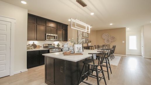 Experience sleek luxury with this kitchen's dark wood cabinetry and pendant lighting at Colony at Pinehurst.