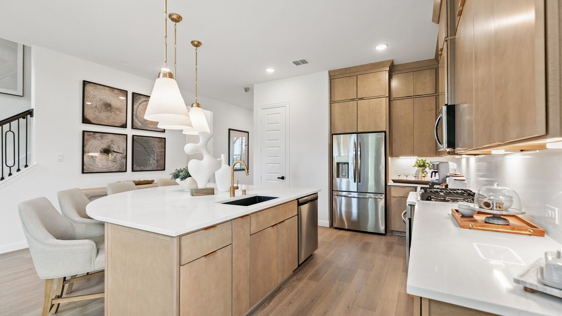 Elegant pendant lights and sleek wood cabinetry define this luxurious Katy Lakes kitchen space.