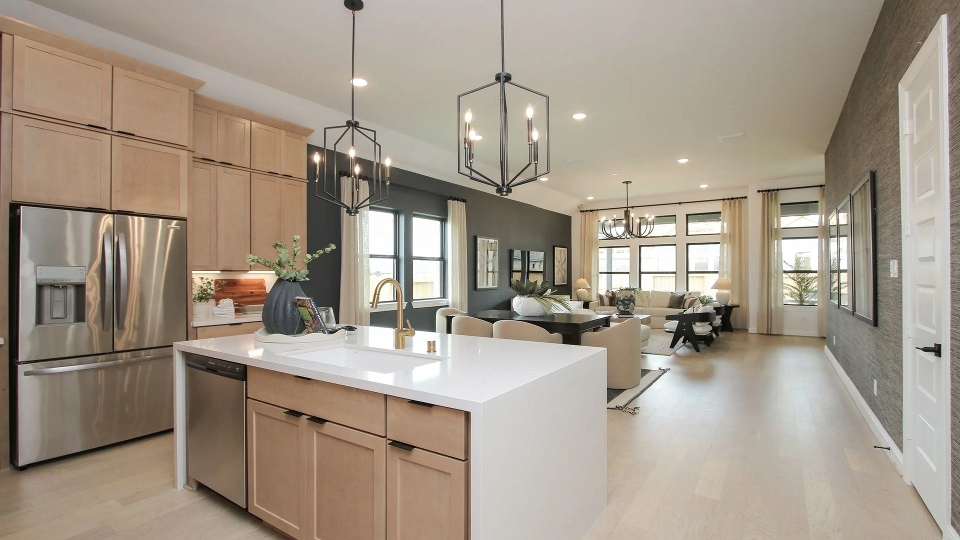 Elegant open-concept design with light wood floors and modern chandeliers in Coastal Point.