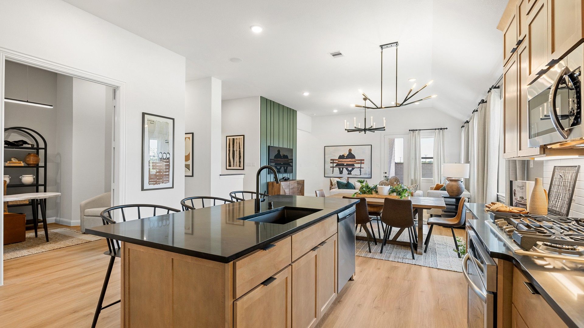 Sleek cabinetry, black island, and elegant chandelier enhance this Southern Pointe open-concept design.