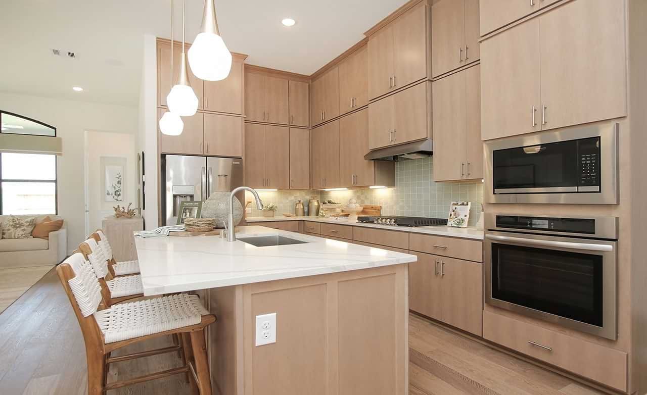 Elegant Sunterra kitchen boasts light wood cabinetry, sleek appliances, and a chic island centerpiece.