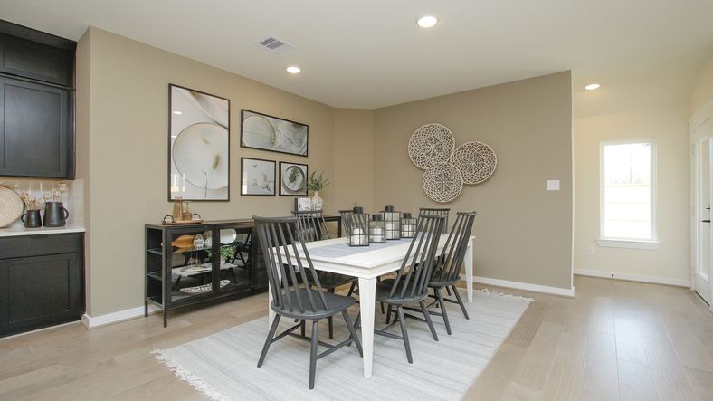 Luxurious dining room boasts stylish wall art and elegant hardwood flooring in Colony at Pinehurst.