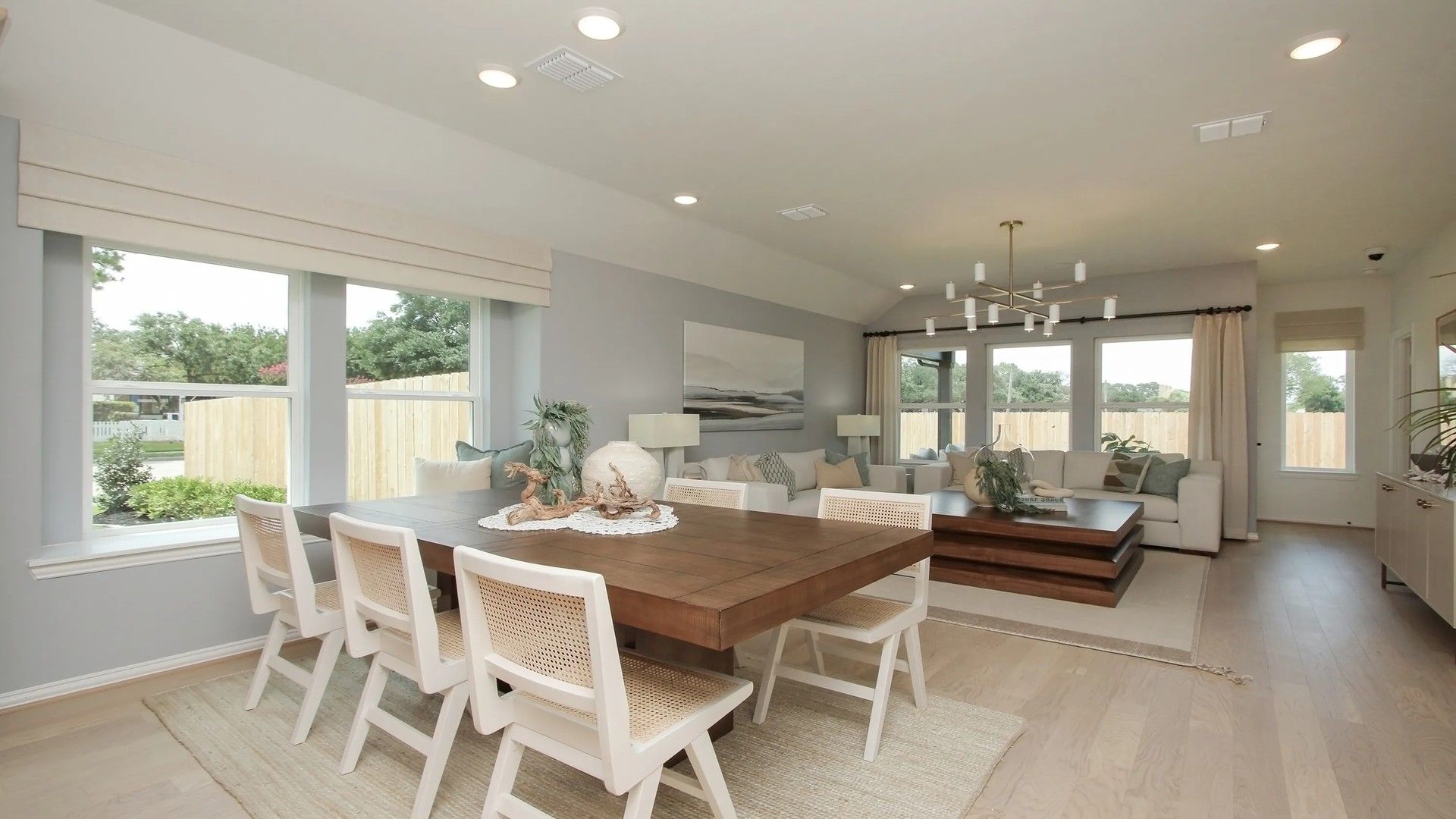 Spacious open-concept living room with custom wood dining table and panoramic windows. Ellis Cove elegance.