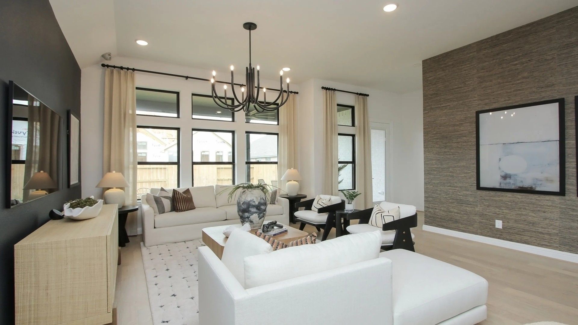Discover elegance in Coastal Point's living room. Modern chandelier, textured accent wall elevate luxury design.