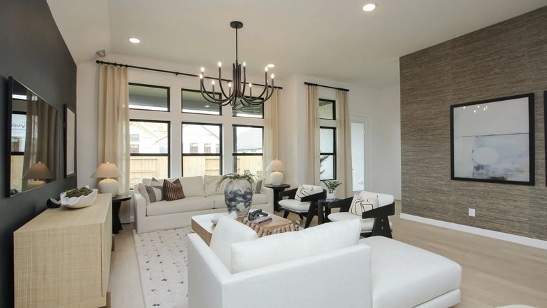 Discover elegance in Coastal Point's living room. Modern chandelier, textured accent wall elevate luxury design.