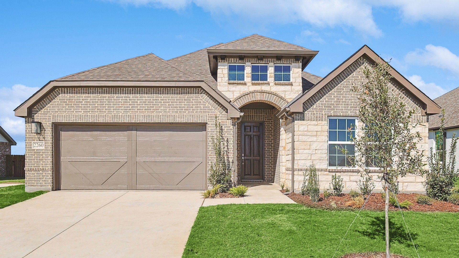 Brick facade, elegant archway, and lush landscaping define this Westland Ranch home.