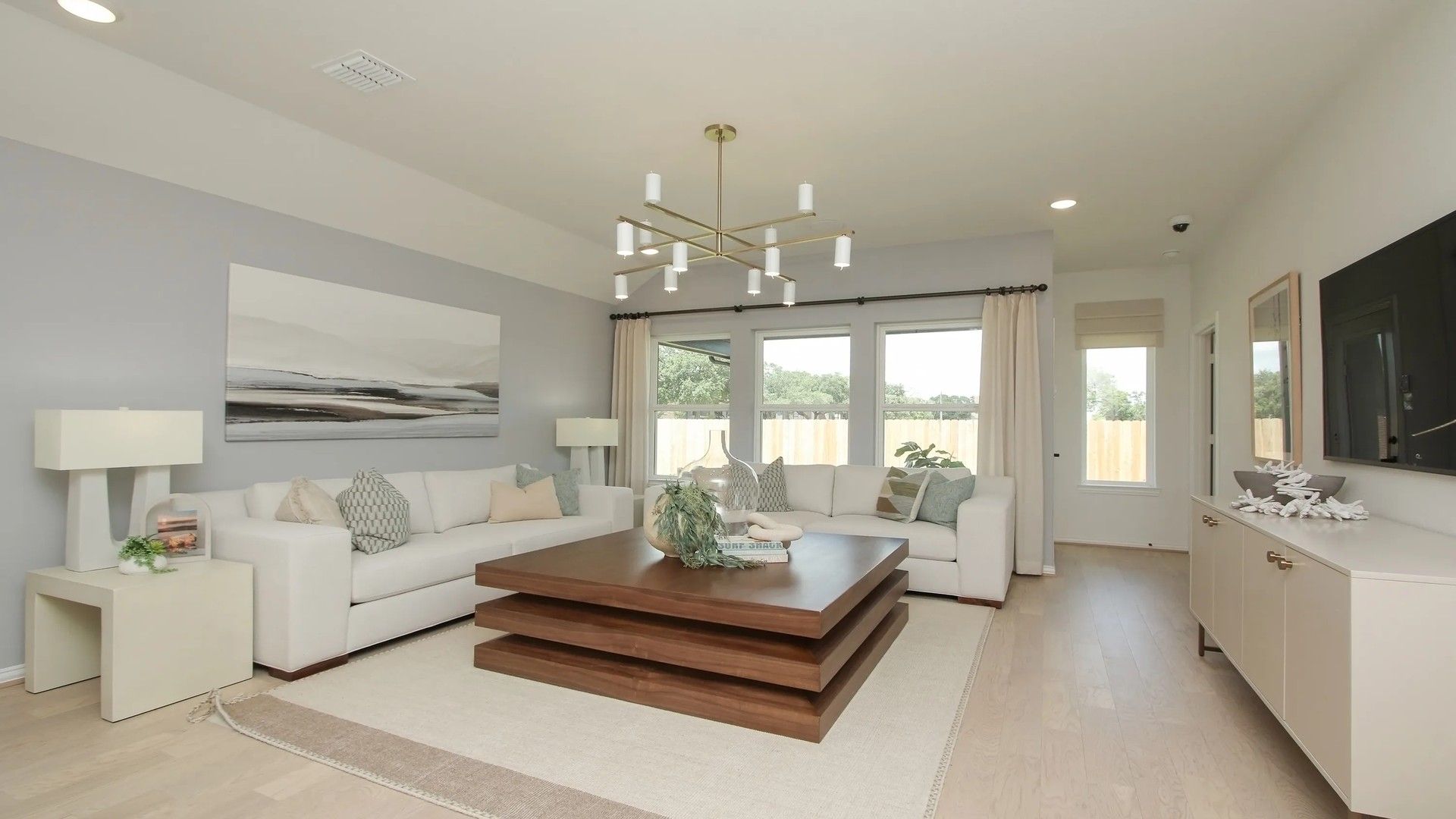 Elegant living room with sleek furnishings, modern chandelier, and expansive windows in Ellis Cove.
