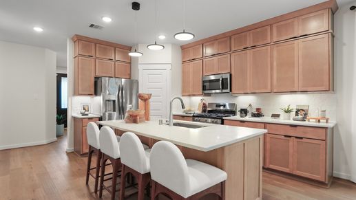 Elegant wooden cabinetry and sleek island enhance this Mostyn Springs kitchen's modern appeal.