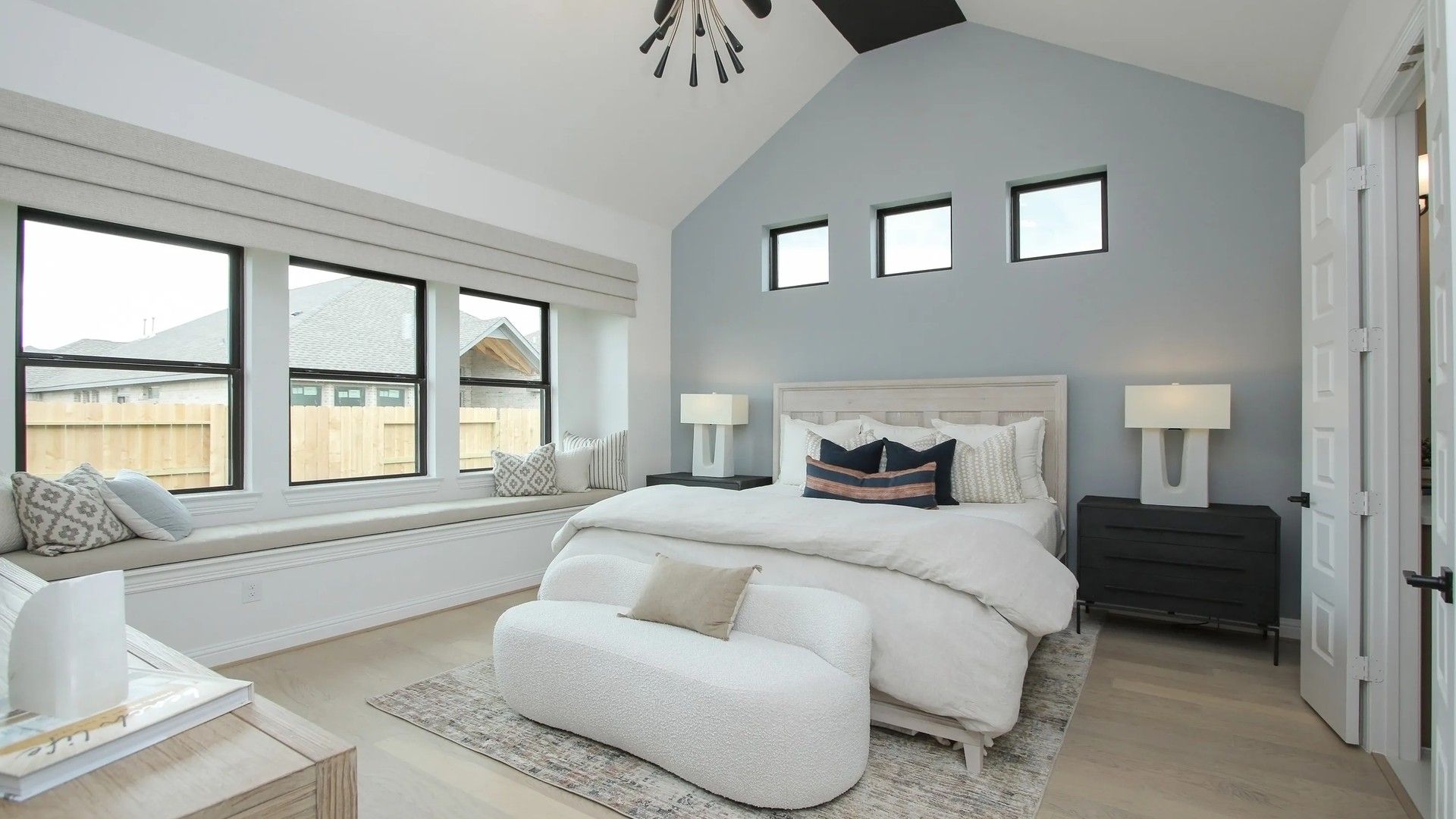 Vaulted ceiling, chic lighting, and expansive windows define this luxury Coastal Point bedroom. Exclusive living space.