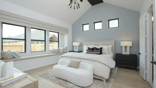 Vaulted ceiling, chic lighting, and expansive windows define this luxury Coastal Point bedroom. Exclusive living space.