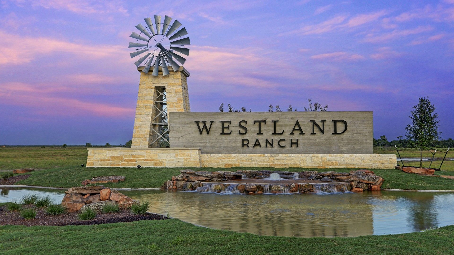 Dramatic stone entrance with striking windmill and serene pond. Westland Ranch, Texas.