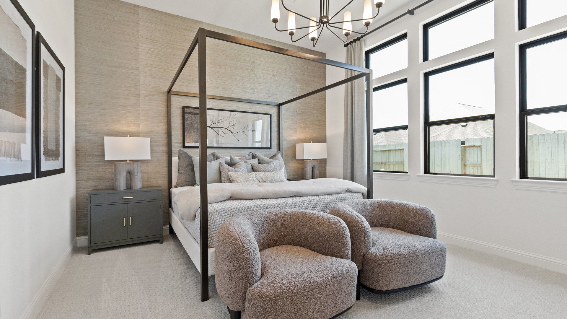 Elegant canopy bed, plush seating, and modern chandelier elevate Oakwood Estates' master bedroom.