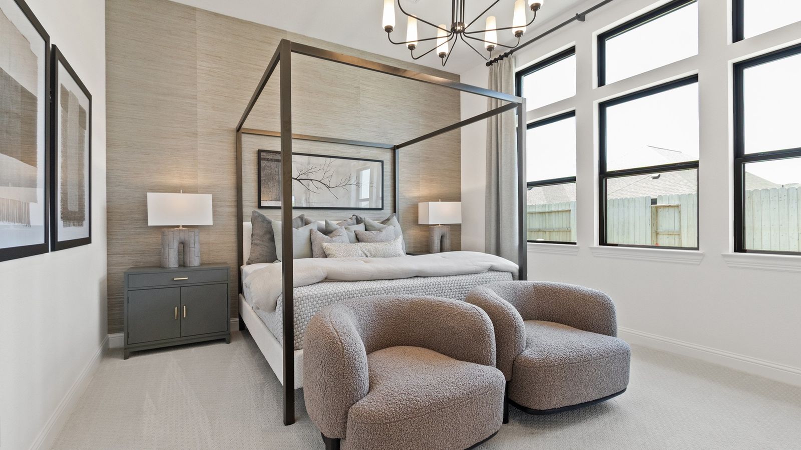 Elegant canopy bed, plush seating, and modern chandelier elevate Oakwood Estates' master bedroom.