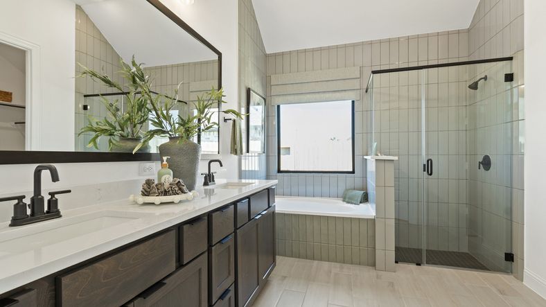 Revel in luxury with dual sinks, dark wood cabinets, glass shower, and soaking tub in Oakwood Estates.