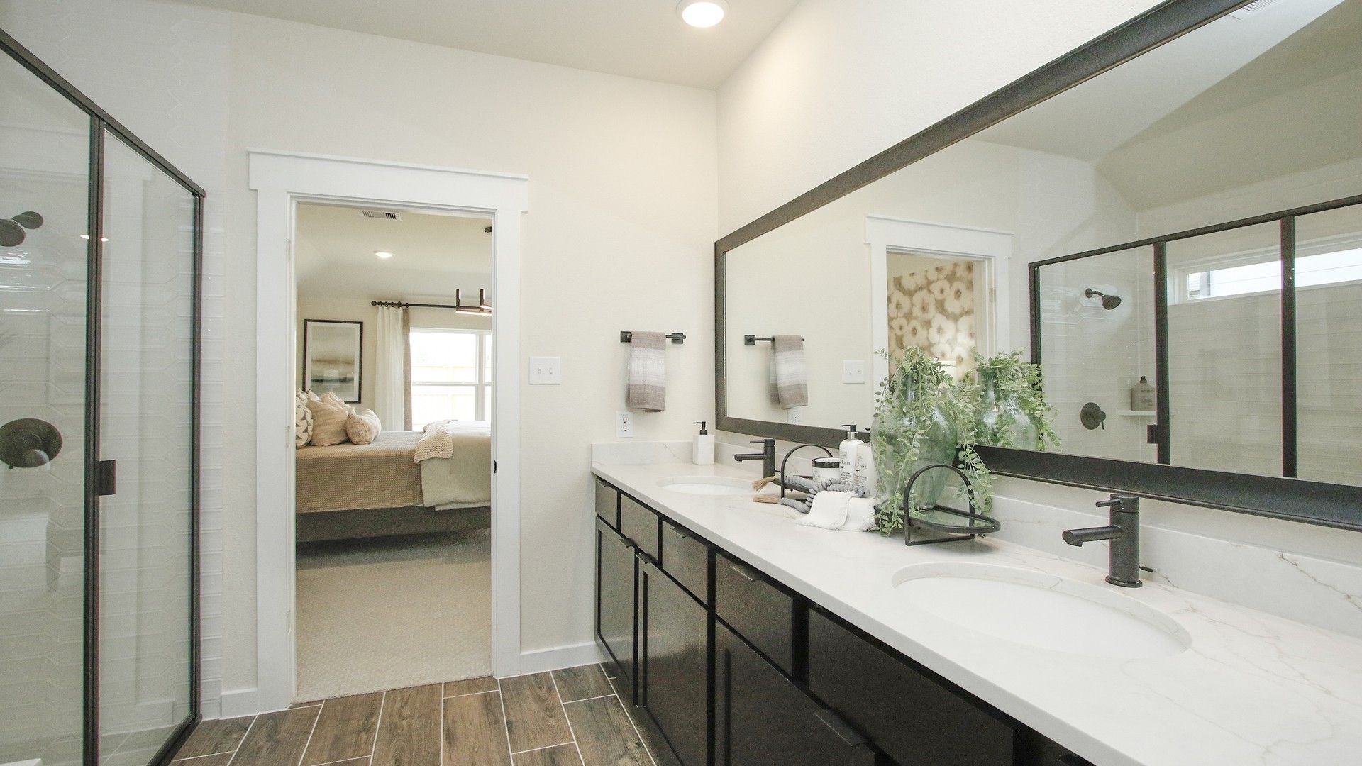 Luxurious dual vanity with marble countertop in Colony at Pinehurst. Elegant glass shower and wooden floors.