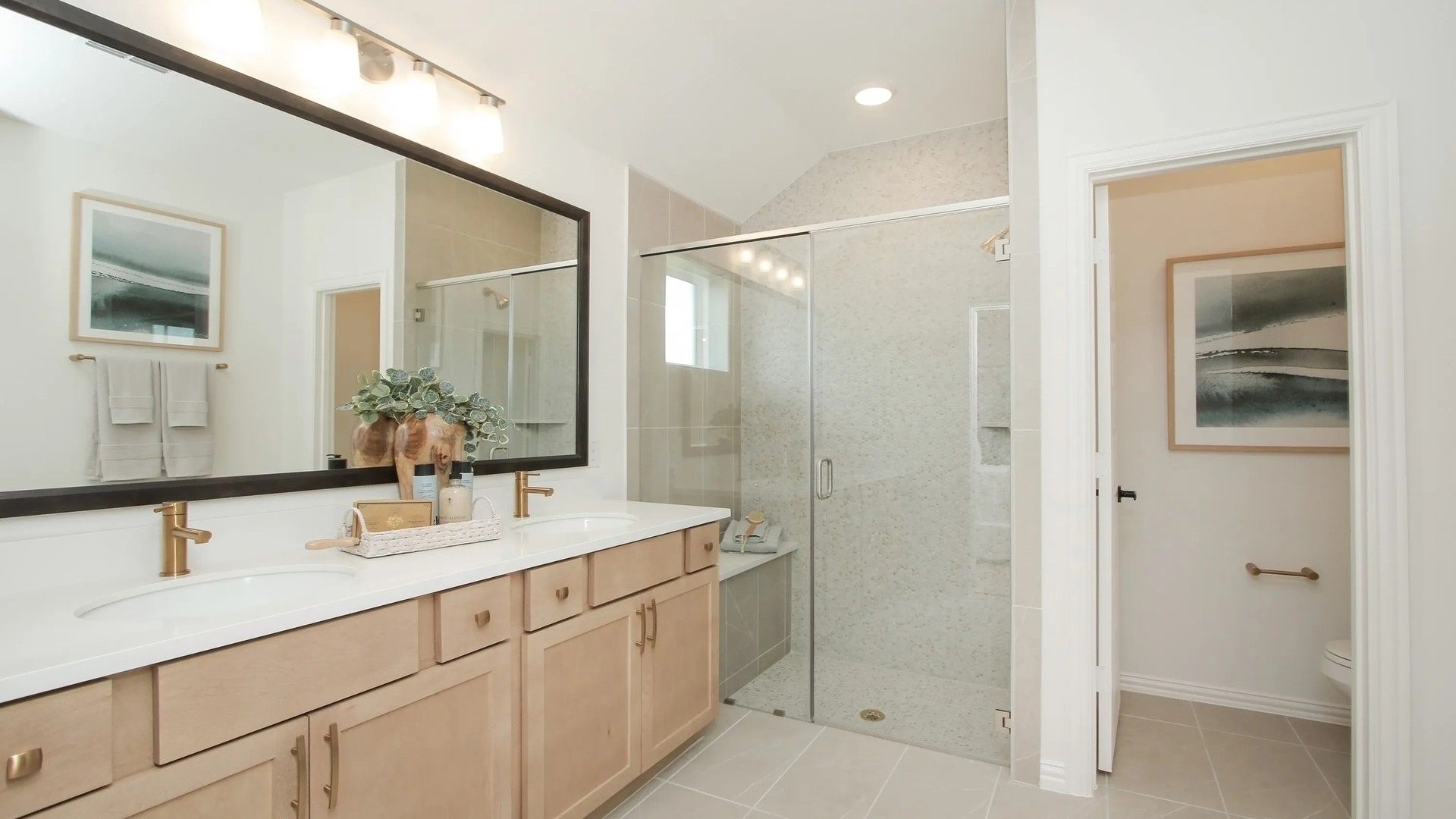 Spacious bathroom with chic dual sinks, elegant glass shower, and refined tilework in Ellis Cove community.