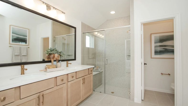 Spacious bathroom with chic dual sinks, elegant glass shower, and refined tilework in Ellis Cove community.