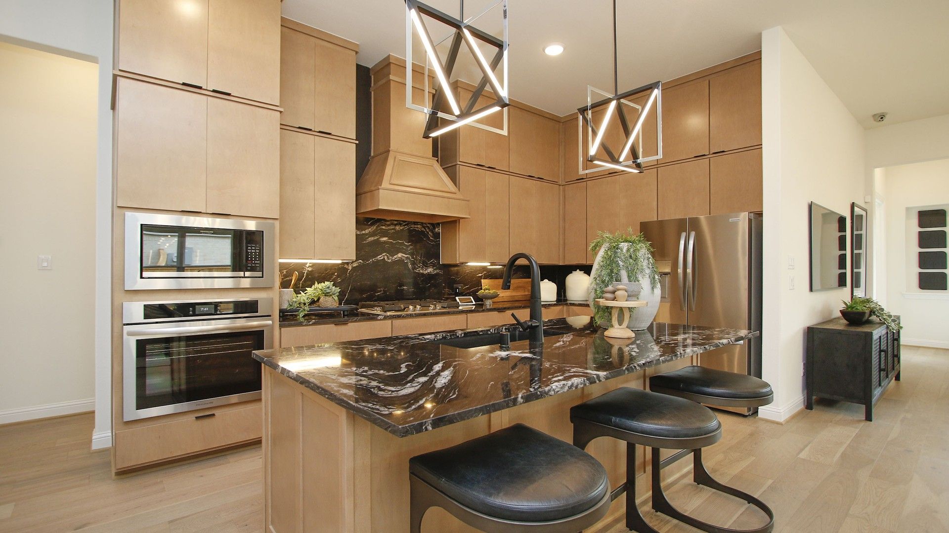 Experience sleek elegance with black marble countertops, custom wood cabinets, and chic geometric lighting in Woodlands Hills.