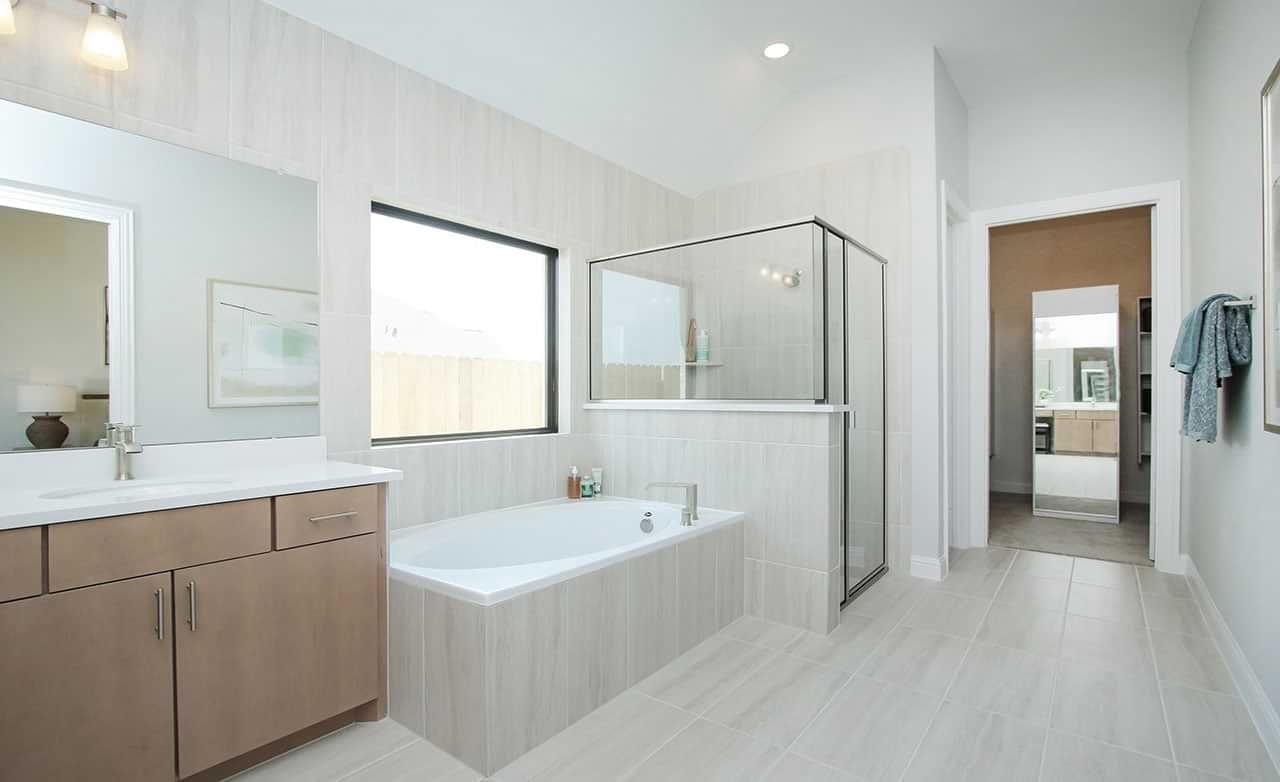 Indulge in the Sunterra community’s luxurious bathroom with a sleek glass shower and refined wood cabinetry.