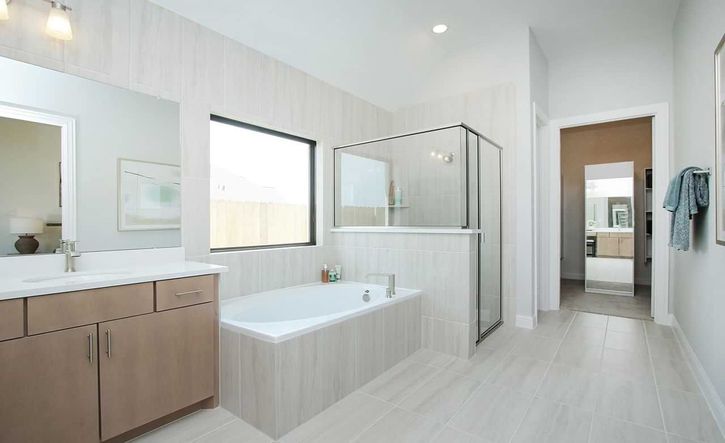 Indulge in the Sunterra community’s luxurious bathroom with a sleek glass shower and refined wood cabinetry.