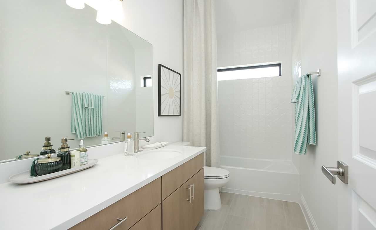 Sleek bathroom features modern vanity, luxurious tiling, and refined finishes in Sunterra community.