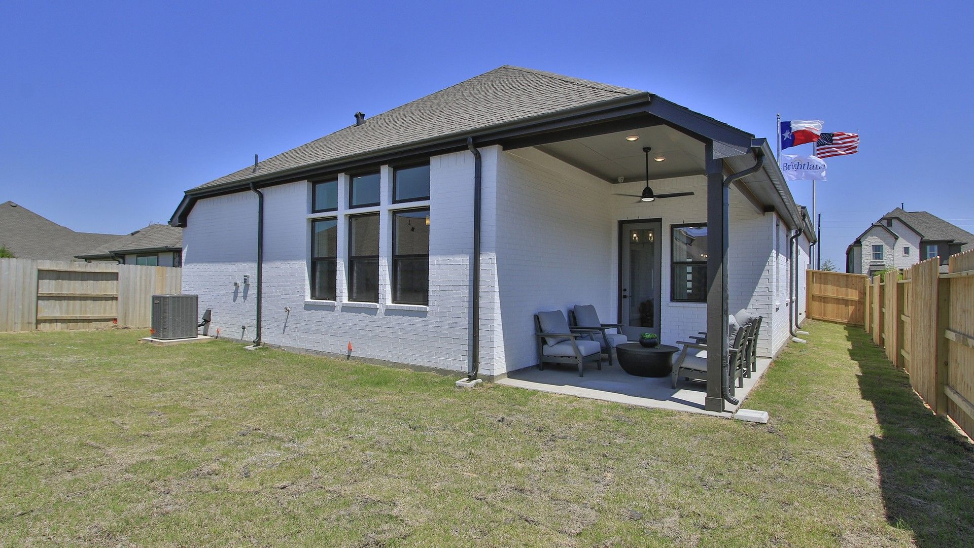 Elegant white brick facade with shaded patio in Oakwood Estates. Enjoy Texas charm and classic design.
