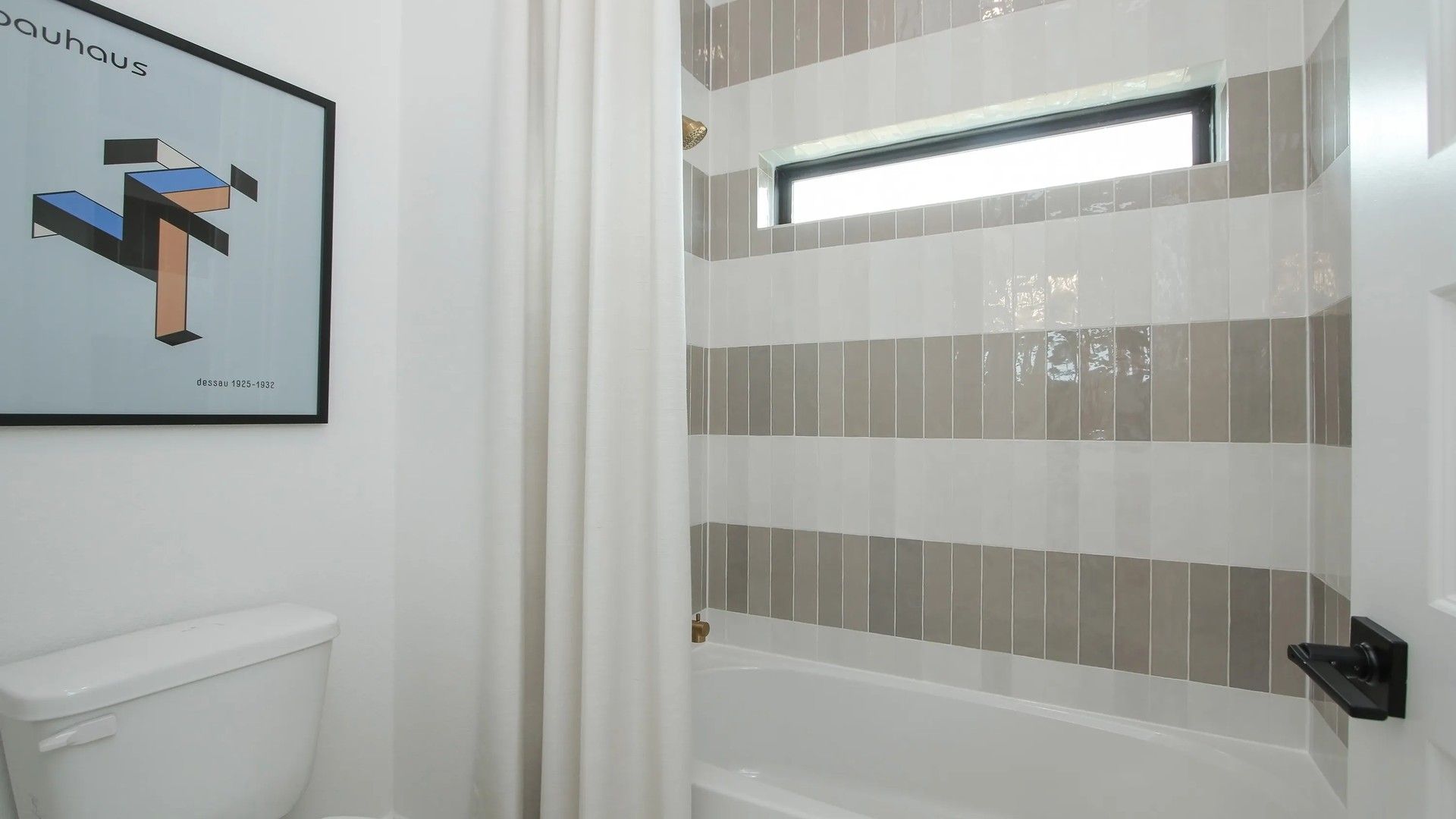 Elegant striped tiles and sleek fixtures enhance this Coastal Point bathroom's modern allure.